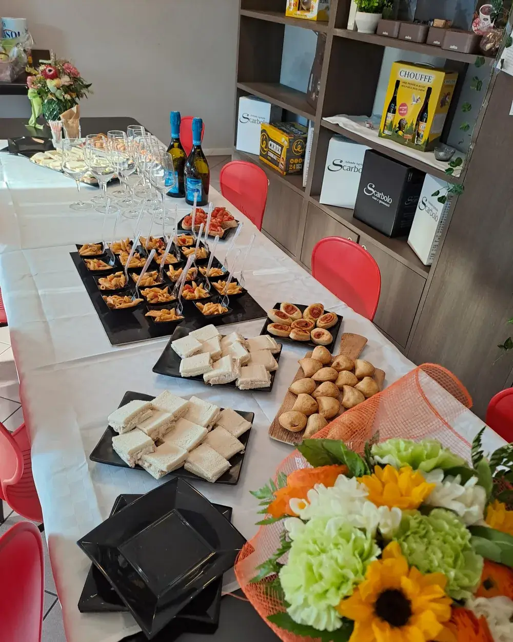 Buffet di tramezzini, rustici e pasta fredda su una tavolata apparecchiata di bianco