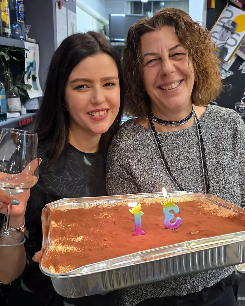 Desirée e Michela dietro al banco di Sbaraglio, sorridenti, con una teglia di tiramisù con le candeline