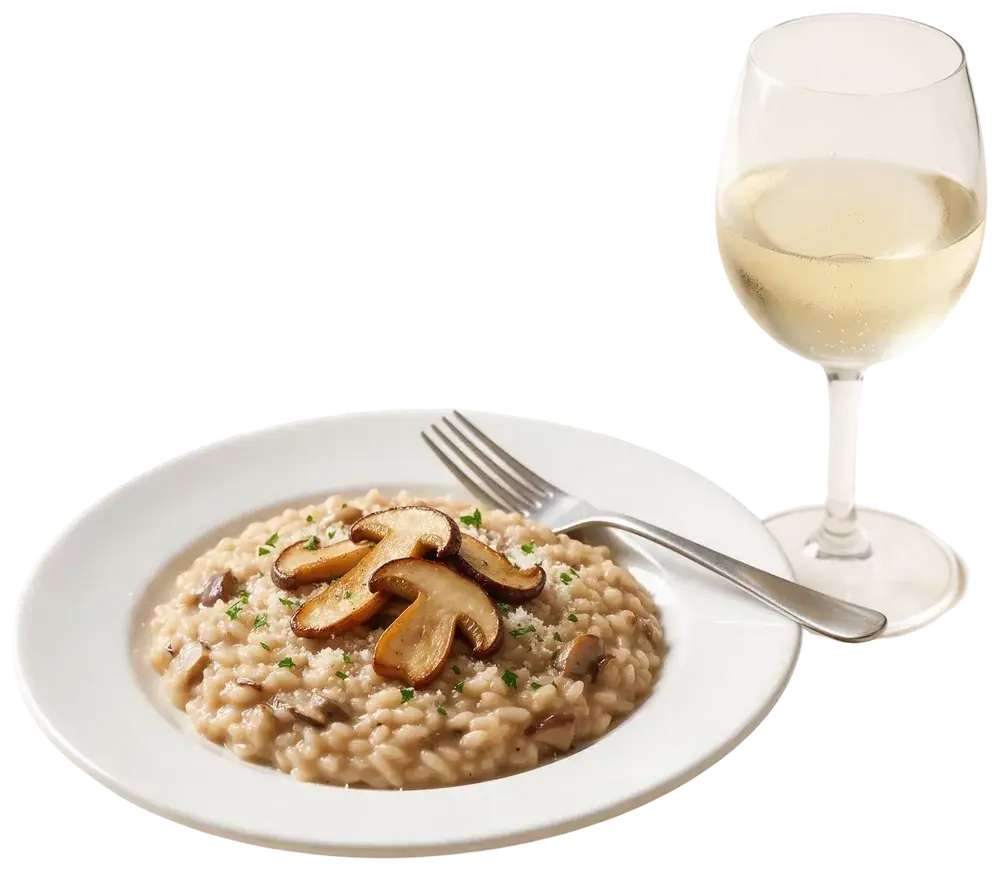 Risotto ai funghi porcini con una forchetta sul bordo del piatto e un calice di vino bianco
