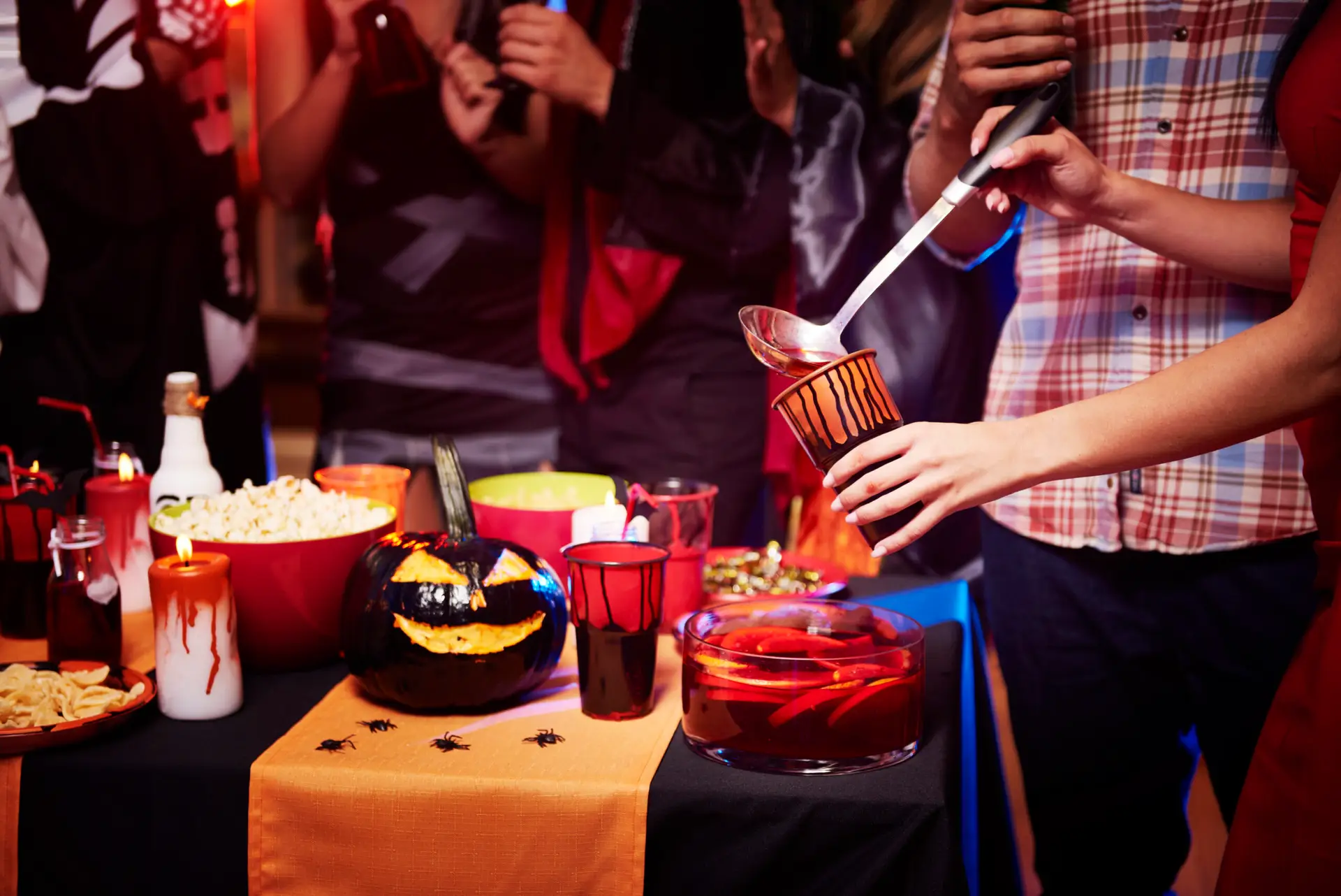 Tavolo apparecchiato per una serata di Halloween, con bicchieri e decorazioni.